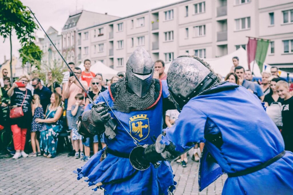 Pojedynek rycerzy w zbrojach, walczących na tle miasta