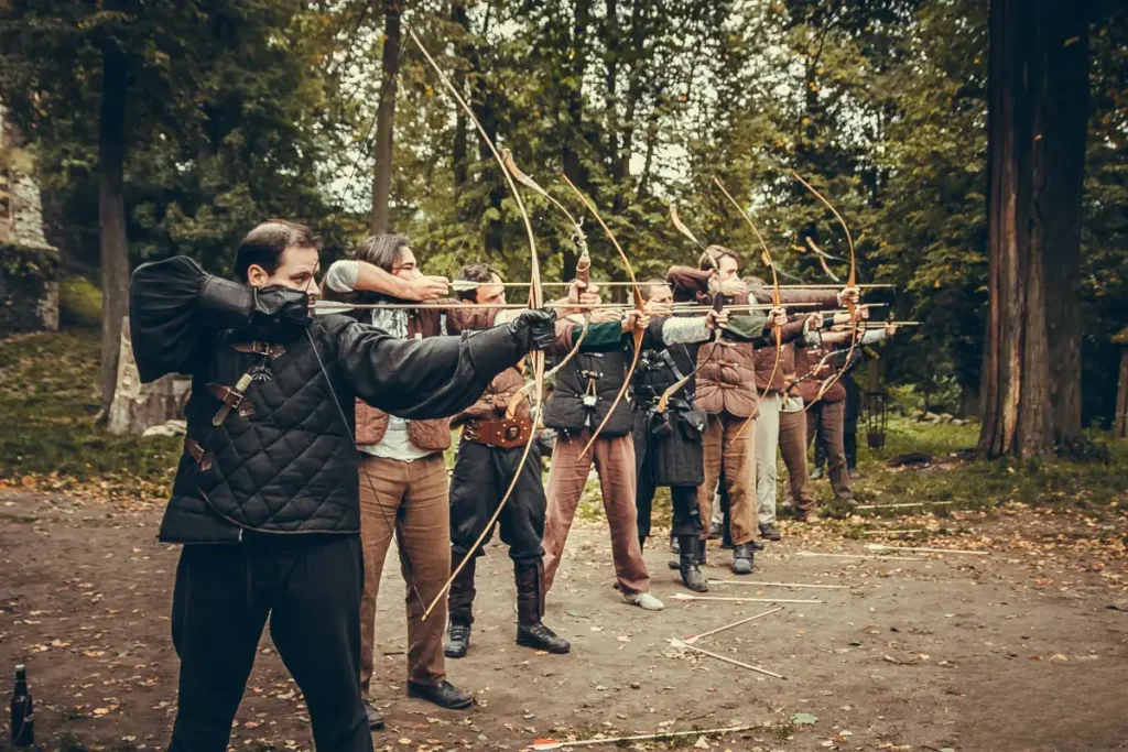 Grupa uczestników strzelających z łuków na warsztatach.